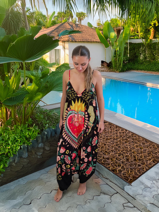 Woman in a colourful jumpsuit standing by a pool with lush greenery around